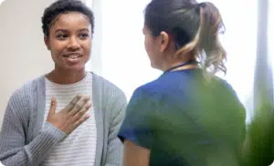 Female patient with hand over chest in conversation with medical staff