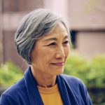 Smiling senior aged Taiwanese woman in blue sweater