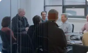 Group of people sitting and conversing around a long conference table